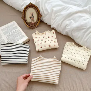 Close-up of four floral and striped toddler girl shirts with ruffled mock neck detailing