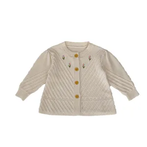 Cremeweiße Strickjacke für Babys mit handbestickten Blumen und Holzknöpfen im Detail
