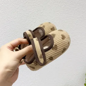 Detail of corduroy baby walking shoes with brown heart patterns and velcro closure