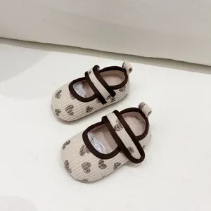 Close-up of baby walking shoes with heart pattern and corduroy texture on soft fabric