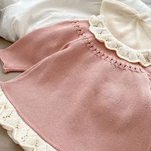 Detailansicht der rosa Strickjacke für Babys mit weißem Rüschenkragen und Spitzenmuster