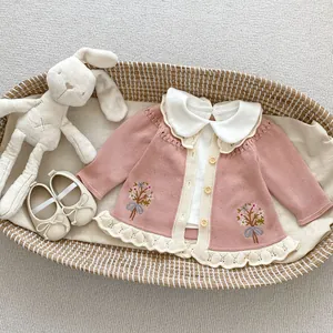 Nahaufnahme der rosa Strickjacke für Babys mit Blumenstickerei und Spitzenbesatz