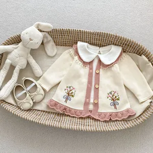 Detail der Baby-Strickjacke mit Blumenstickerei, Bubikragen und echten Holzknöpfen