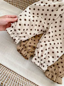 Close-up of baby corduroy pants with coffee brown polka dots and elastic cuffs