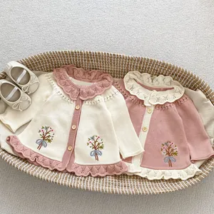 Makro-Detail von Baby-Strickjacke mit Blumenstickerei und gewelltem Rüschenkragen