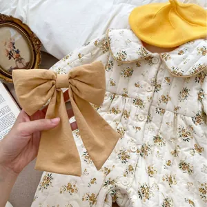 Quilted floral baby romper with Peter Pan collar and bow headband in a vintage setting