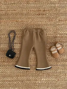Detail of girls flared corduroy trousers with elastic waist and wavy hem decoration