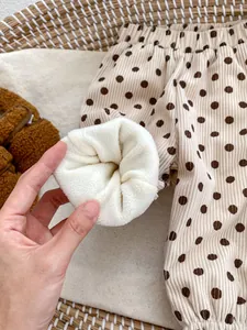 Detail showing the thick fleece lining and corduroy fabric of these beige polka dot kids pants