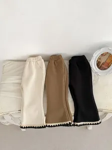 Detail of flared cuffs with lace trim on girls thick ribbed knit trousers in three colors