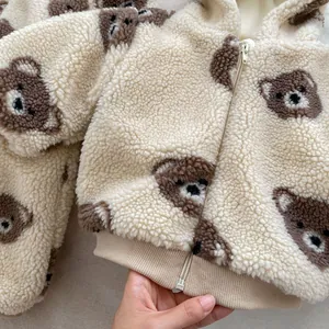 Close-up of baby sherpa fleece jumpsuit showing soft bear pattern and zipper detail