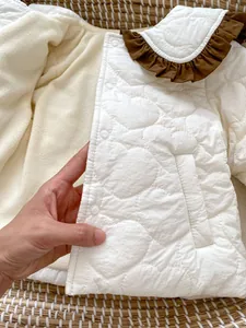 Détail de la veste d'hiver bébé avec surpiqûres cœur, col à volants et doublure polaire