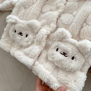 Détail du cardigan bébé en polaire crème avec poches ours mignon et texture douce