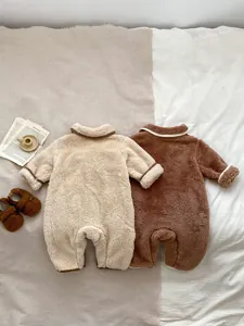 Due calde tutine in pile per neonati color crema e marrone adagiate su un morbido letto
