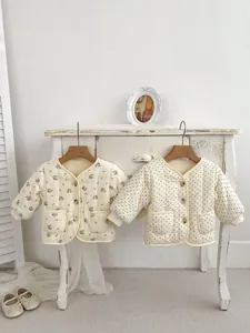 Detail von gesteppten Baby-Strickjacken mit V-Ausschnitt und Vintage-Knöpfen am Schrank