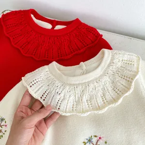 Détail d'une barboteuse en tricot pour bébé avec col en dentelle et broderie florale