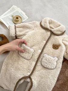 Dettaglio della tutina neonato in pile beige con ricamo a orso e tessuto morbido