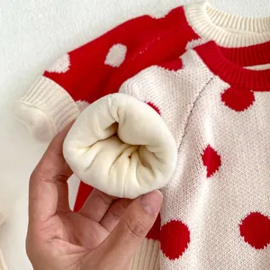 Détail du pull pour bébé montrant la doublure en peluche épaisse et le tricot à pois rouges