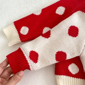 Détail du pull en tricot à pois rouges et blancs avec poignets côtelés et texture