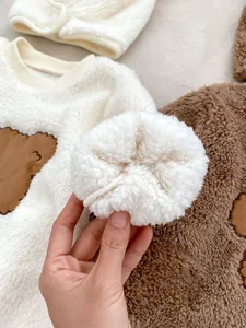 Close-up of thick fleece sleeve cuff and cartoon bear embroidery on baby romper