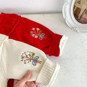 Détail de la barboteuse en maille pour bébé avec broderies florales et nœuds