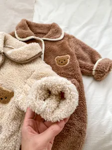 Dettaglio tutina neonato in peluche che mostra tessuto in pile e ricamo di orsetto