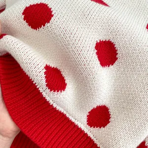 Vue détaillée du tissu en tricot blanc à pois rouges avec poignets côtelés doux