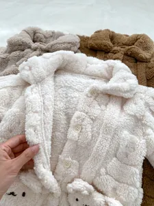Detailansicht von Teddy-Fleece-Stoffproben in Weiß, Grau und Braun für Babykleidung