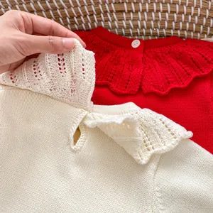 Détail de la barboteuse en maille pour bébé avec col en dentelle et boutonnière