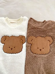 Detail of baby bear fleece onesies showing plush textures in cream and coffee brown colors