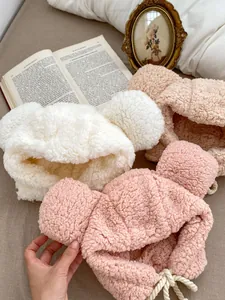 Detail of plush baby hats with bear ears and braided chin straps in three warm colors