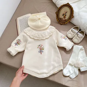 Détails de broderie florale et col en dentelle sur cette barboteuse beige pour bébé