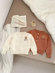 Detail van gebreid babyvestje met berenborduursel en fijne golvende ribboorden