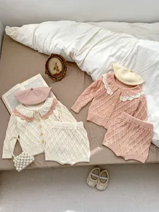 Détails de tricot à losanges, col festonné ajouré et boutons en bois sur cardigan bébé