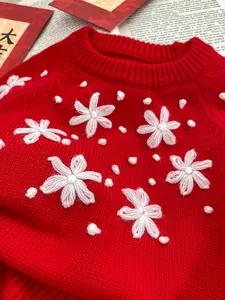 Close-up of red knit baby romper with white 3D flower embroidery and dot texture