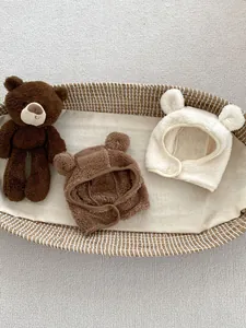 Detail of plush baby bear ear hats in dark brown and beige on a soft textured background
