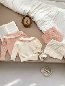 Détail de l'ensemble en tricot pour bébé avec cardigan losanges et short en coton