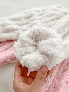 Detail of soft pink and white fleece fabric with textured rope pattern and fluffy pompom