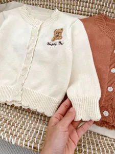 Detailopname van gebreid babyvest met geschulpte randen en schattig berenborduursel