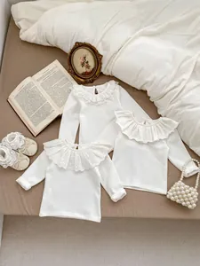 Detailed view of white baby blouses featuring ruffled lace collars and soft cotton fabric