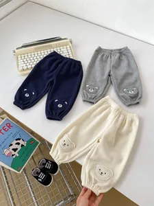 Flat lay of baby waffle pants with cute bear embroidery and elastic cuffs on neutral background