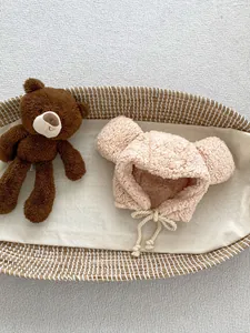 Detail of light pink baby fleece hat with cute bear ears in a woven cradle