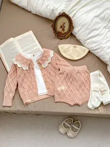 Détail du cardigan en tricot rose pour bébé avec col en dentelle et béret assorti