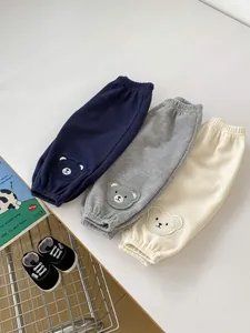 Close-up of waffle knit baby joggers in navy, grey, and cream with cute bear patches