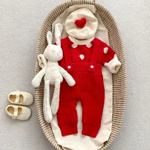 Vue détaillée d'un ensemble bébé tricoté avec bonnet cœur et barboteuse à pois dans un panier
