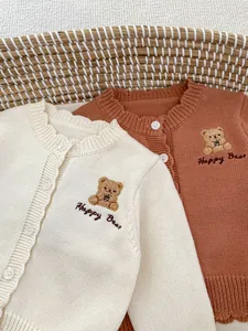 Detail van gebreid babyvest met berenborduursel en zachte geribbelde textuur in een mand
