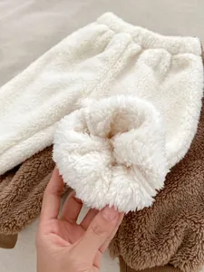 Close-up of thick polar fleece lining on winter baby trousers in white and brown