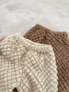 Detailed close-up of cream and brown thick fleece baby pants with diamond texture