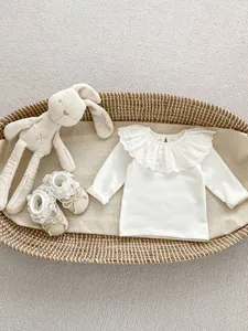 Detail of white cotton baby top featuring oversized eyelet lace embroidery collar