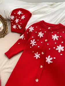 Detail of red knitted baby romper with handmade floral embroidery and matching ear hat