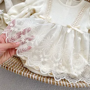 Close-up of baby romper featuring delicate waffle fabric and intricate floral lace embroidery